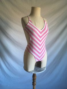 vintage 1980s swimsuit Gottex Jrs. 45% cotton, 45% polyester, 10% lycra white and pink chevron striped plunge back sides of body are partly exposed cross back straps lined panty/bust good vintage condition light wear- light stains-see photos  labeled size is outdated, smaller- like a xs, see below measures, lying flat, chest-12" to 17" stretched waist-9 1/4" (sides are open) hip-13" to 18 1/2" stretched panty width-2 1/2" length-25" to 30" Pink Cotton Swimwear For The Pool, Fitted Striped Swimwear For Poolside, Fitted Striped Swimwear For Spring, Spring Striped Cotton Swimwear, Fitted Striped Swimwear For Summer, Summer Striped Fitted Swimwear, Fitted Striped Summer Swimwear, Striped Sleeveless Fitted Swimwear, Fitted Striped Sleeveless Swimwear