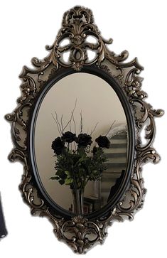 there is a vase with flowers in it and a mirror on the wall behind it