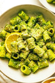 a white bowl filled with broccoli covered in parmesan cheese and lemon wedges