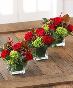 three clear vases filled with red roses and greenery