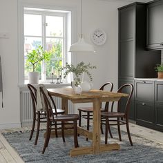 a dining room table with four chairs and a clock on the wall