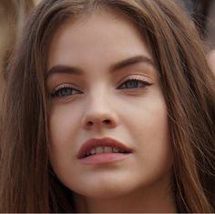 a close up of a woman with long hair and blue eyes looking at the camera