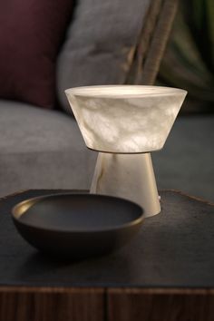 a white bowl sitting on top of a table next to a black plate and chair