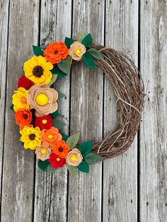 a wreath made out of paper flowers sitting on top of a wooden floor next to a fence