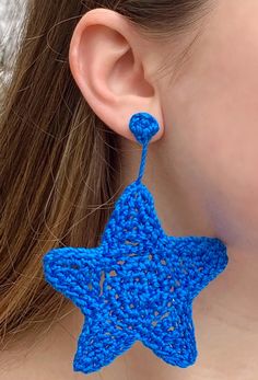 a woman wearing blue crocheted earrings with a star shaped design on the ear