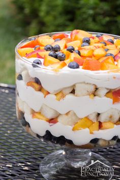 a trifle with fruit and cream on top is sitting on a table in the garden