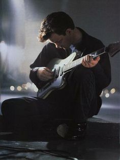 a man sitting on the ground playing an electric guitar