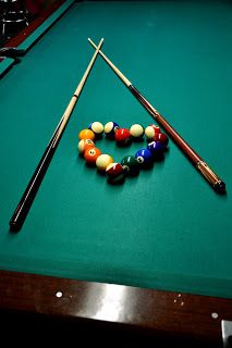 billiards balls and cues on a pool table with the cues in position