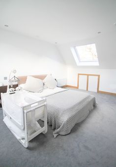 a white bed sitting in the middle of a bedroom next to a window on top of a wall