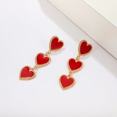 red heart shaped earrings sitting on top of a white surface