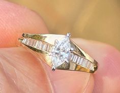 a woman's hand holding a yellow gold ring with a diamond in the center