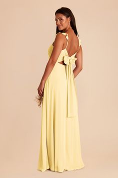 the back of a woman wearing a yellow dress with a large bow at the waist