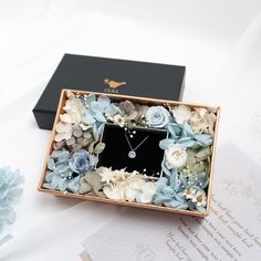 a box that has some flowers in it and a necklace on the inside of it