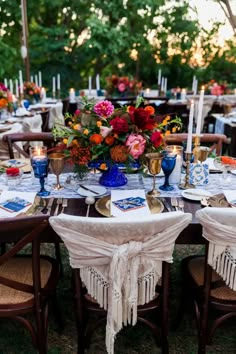 an outdoor table set with place settings and flowers