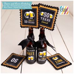 two beer bottles are sitting next to each other on a table with black and gold decorations