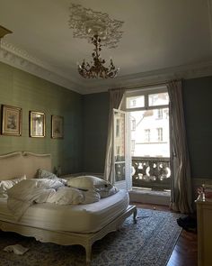 a bed sitting in the middle of a room with a chandelier above it