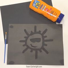 an orange glue bottle sitting on top of a piece of paper next to a drawing