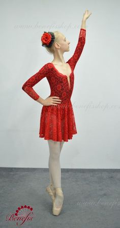 a woman in a red dress is holding her hand up to the side while wearing ballet shoes