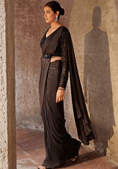 Introducing the Black Pre Drape Saree Set - an exquisite blend of elegance and convenience. This stunning black drape saree is crafted from a comfortable pleated fabric, ensuring effortless draping. The accompanying full-sleeved blouse features delicate tonal bead work in a mesmerizing floral pattern. To add the perfect finishing touch, this set includes a tasselled belt. With its ready-to-wear design, this ensemble offers both style and ease. Embrace sophistication with the Black Pre Drape Saree Set. Composition : Saree and Blouse -Pleated Blend, Lining - Shantoon Care: Dry Clean Only and Vacuum Storage This product can be customized for sleeves, length of blouse and neckline Delivery : 6-8 weeks as the product is hand crafted. Check Size Guide or choose MySize for free customisation (All Elegant Black Pre-draped Saree, Black Draped Saree With Sheer Dupatta, Black Bollywood Style Pre-draped Saree, Black Bollywood Pre-draped Saree, Festive Black Draped Saree, Black Georgette Draped Saree, Black Draped Georgette Saree, Black Pre-draped Saree With Sheer Dupatta, Black Pre-draped Saree For Party