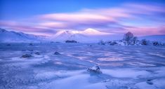 the snow covered ground has ice on it and mountains in the distance with pink clouds