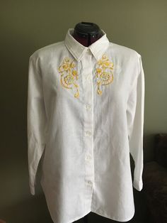 "Handmade ladies embroidered western shirt is a size extra large made in white cotton fabric.   This shirt has 3 tones premium yellow rayon embroidery thread with gold metallic thread in design.  Front button closure with white buttons that have a delicate flower design to compliment design on shirt.  Shirt measures 24\" flat from side to side, length is 14\" from underarm to hem, with 17.5\" sleeves.  Cotton has been prewashed prior to construction to minimize any shrinkage.  Made in Nova Scotia" White Long Sleeve Shirt With Machine Embroidery, Fitted White Tops With Machine Embroidery, Fitted White Top With Machine Embroidery, White Fitted Top With Machine Embroidery, Spring Embroidered Gold Top, Summer Embroidered Gold Tops, Embroidered Gold Top For Spring, Embroidered Gold Tops For Summer, Gold Embroidered Summer Tops