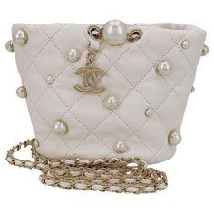 Store item: 67973 Chanel 21S White Cream About Pearls Bucket Bag Mini is a pillowy soft miniature bucket bag adorned with gold-pronged faux pearls and dangling CC charm hardware, with a woven crossbody strap. Perfect for evening or everyday, with easy access to essentials. In Cream lambskin leather and shiny gold hardware. This item is in excellent condition with very few signs of normal use. Corners are clean with no rubbing or scuffing. Hardware is clean and shiny. Interior is clean. Please view all 12 to 16 photos of the actual bag, for details, and ask any questions. Measures 6in. W (at widest point) x 4.5in. H x 4.2in. D, strap drop is 19.5 inches For 19 years, Boutique Patina has specialized in sourcing and curating the best condition vintage leather treasures by searching closets ar Chanel Pearl Bag, Chanel Bucket Bag, Navy Clutch, Navy Blue Purse, Chanel Pearl, Vintage Chanel Bag, Mini Bucket Bag, Chanel Pearls, Chanel Mini