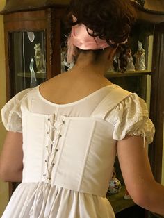 A corset from the early 19th century, 1st Empire or Regency. It is a short corset that is laced in front and behind, which allows an impeccable adjustment with the lacing.  Size M corresponding to 82cm under the chest, this corset is suitable for a B or C chest. Carefully made in soft white cotton, it requires a delicate wash at 30 C degrees. Worn over the day shirt, it will be your Jane Austen, Bridgerton or Napoleon costume accessory. White Fitted Corset With Lace-up Back, White Lace-up Back Fitted Bodice Corset Dress, White Corset Dress With Lace-up Back And Fitted Bodice, Regency Style Corset Dress With Boned Bodice, Victorian White Underbust Corset, White Underbust Bodice With Lace Trim, Regency Style Overbust Corset Dress With Historical Design, Regency Style Corset Dress With Corset Back For Wedding, Regency Style Corset Back Dress For Wedding