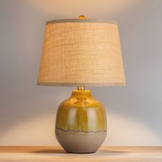 a lamp on a table next to a wall with a blue and white vase underneath it