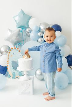 a little boy standing in front of a cake