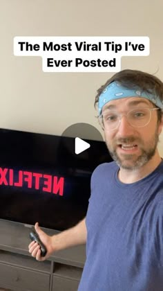 a man holding a remote in front of a tv with the words netflix on it