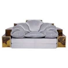 a white and gold couch sitting on top of a wooden table next to a pillow