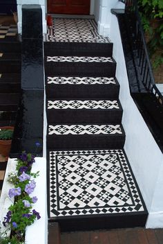 the stairs are decorated with black and white tiles, along with potted plants on either side