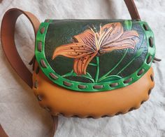 "This leather hippie style bag is actually made from an old 1970's bag pattern that we found, so it has a real retro style that I've always liked! It is made of a goldish-tan cowhide with dark green bullhide on the gusset. This one has a long shoulder strap that can cross over the body or be worn on the shoulder.  The front panel is made of vegetable tanned leather with a hand tooled and painted design by me, my partner did the sewing on the bag. The design is of a Tiger Lily and I did this freehand with no pattern so it is a one of a kind! The panel is finsihed with a sturdy acrylic leather finish to protect the paint. The bag is 9\" wide at the widest point, 7\" tall, and the bottom is about 3\" deep. The strap is 1.25\" wide and 50\" long." Artisan Hand Painted Brown Bags, Hand Painted Brown Shoulder Bag Gift, Hand Painted Brown Rectangular Shoulder Bag, Hand Painted Brown Satchel Shoulder Bag, Brown Hand Painted Satchel Shoulder Bag, Green Hand-tooled Leather Shoulder Bag, Brown Hand Painted Satchel Bag, Coos Bay, Tan Cowhide