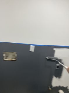 a man is painting the wall with blue tape and white paint on it in an office