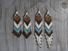 three pairs of beaded earrings are hanging on a wooden surface with wood planks in the background