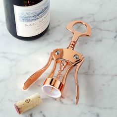 a wine bottle and corkscrew on a marble counter top next to a bottle opener