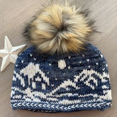 a knitted hat with a star on the side and a pom - pom