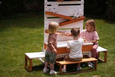 two children are playing on a bench made out of wood and white painted furniture in the grass