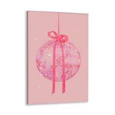 a pink christmas ornament with a bow hanging from it's side on a string