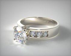 a white gold engagement ring with three stones on the side and a channeled band