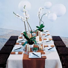 the table is set with white flowers and place settings for two people to sit at