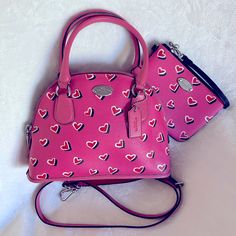 Coach K1481 Mini Cora Dome Satchel Bag & K1495 Wristlet “Valentine’s” Pink W/ Red Hearts Matching Set Simply Beautiful Matching Coach Set In A Gorgeous Barbie Pink Color With Read Hearts Print. Please See All Photos. Preloved W/ Signs Of Usage Throughout But Nothing That Takes Away From The Beauty Of This Set! Bag Measures Approximately 3” D X 9.75” L X 8” H, Excluding Handles. Crossbody Strap Is Adjustable & Detachable W/ Max Drop Of Approximately 24”. Purchase Will Come With Multiple Mini Coach Items/Accessories Friendly Seller, Fast Shipping, Smoke Free & Pet Free Home Pink Coach Bag For Valentine's Day, Pink Top Handle Bag For Valentine's Day, Luxury Coach Bags For Valentine's Day, Coach Heart-shaped Bag For Valentine's Day, Coach Bags For Valentine's Day Gift, Barbie Pink Color, Hearts Print, Coach Crossbody, Coach Crossbody Bag