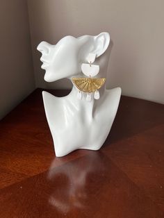 a pair of earrings sitting on top of a white mannequin's head