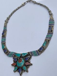 This OUTSTANDING  statement Necklace is an absolute one of a kind treasure.  It is a beautifully handcrafted Tibetan necklace featuring Coral, Turquoise and Lapis Lazuli mosaic plating and carved silver plated findings. They won't be ever the same because of their handmade nature. This necklace is sure to get you noticed for all the right reasons!  Absolutely amazing Unique Blue Necklace With Inlay, Bohemian Pendant Necklaces With Inlay, Traditional Turquoise Necklace For Festivals With Silver Accents, Traditional Silver Turquoise Necklace For Festivals, Bohemian Pendant Necklace With Inlay, Handmade Silver Turquoise Necklace For Festivals, Traditional Turquoise Inlay Necklace As Gift, Traditional Turquoise Necklace With Inlay For Gift, Traditional Blue Turquoise Necklace With Inlay