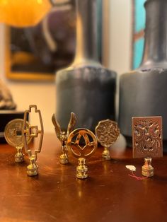 four pieces of brass sitting on top of a wooden table in front of vases