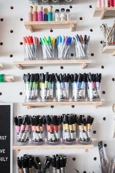 the wall is filled with lots of markers and crayons on wooden shelving