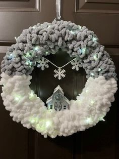 a wreath with lights and snowflakes hanging from the front door to decorate it