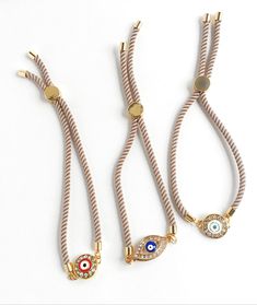 "Beautiful pave evil eye bracelets with a champagne color Milan Rope closure. Closure is adjustable and convenient. ✨Fun Fact✨ The evil eye, known as \"mati\" (μάτι) in Greek culture, is a curse thought to be given by a malicious glare that can cause bad luck or loss. That's why it's important to wear an evil eye somewhere on your body to ward off this curse and protect yourself throughout the day. 👀 So, this HeartString Evil Eye bracelet not only is chic and beautiful, but possibly help you wa Adjustable Round Beige Bracelets, Adjustable Beige Bracelets, Adjustable Beige Round Bracelets, Adjustable Beige Jewelry, Adjustable Length Beige Jewelry, Adjustable Gold Evil Eye Bracelet For Everyday, Adjustable Beige Jewelry With Sliding Knot, Beige Jewelry With Adjustable Length For Gift, Beige Jewelry Gift With Sliding Knot