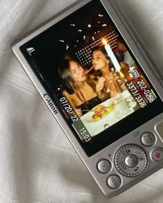 a cell phone with two girls on the screen and a candle in front of them