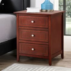 a night stand with two drawers and a blue lamp on it in a bedroom next to a bed